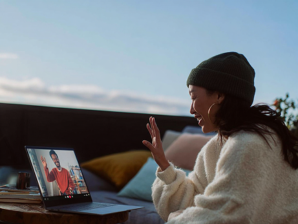 Woman sitting on a couch outdoors, using a laptop for an Arrows video date with her match.